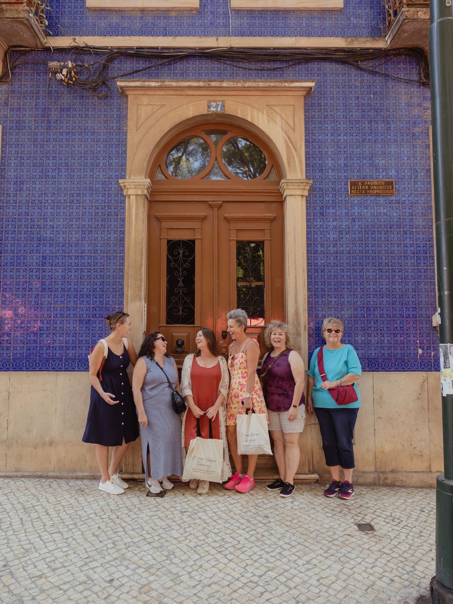 A group of women traveling together in front of a building in Lisbon. 