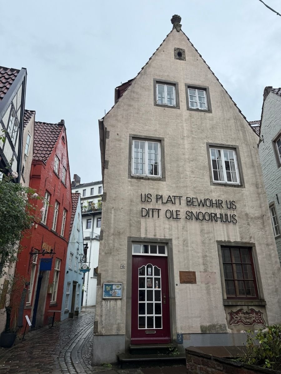 The facade of a gabled house proudly bearing the inscription “Us platt bewohr us ditt ole snoorhuus” (Our Low German preserves this old Schnoor house), representing the heart of Bremen’s preserved medieval charm.