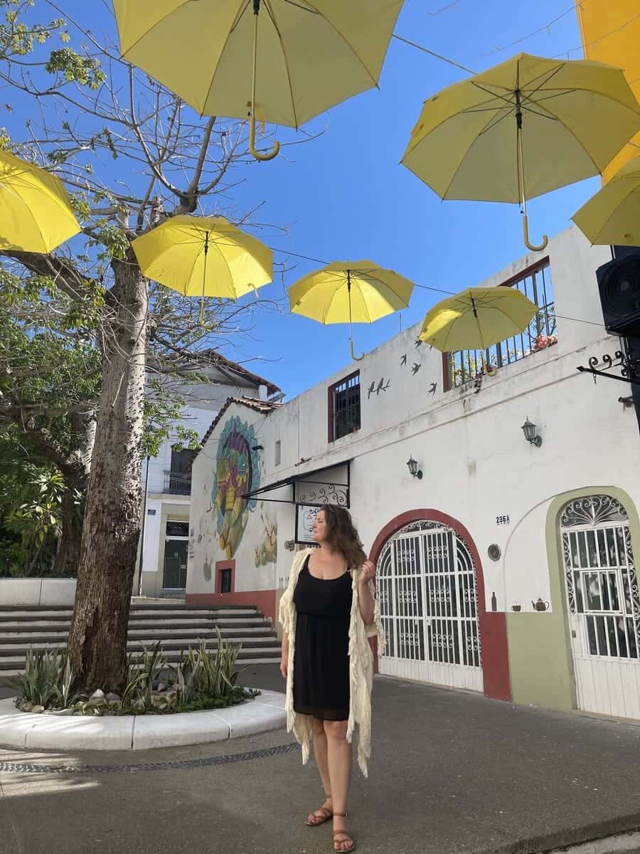 A single woman in the square of alone in Puerto Vallerta with yellow umbrellas above as a decoration