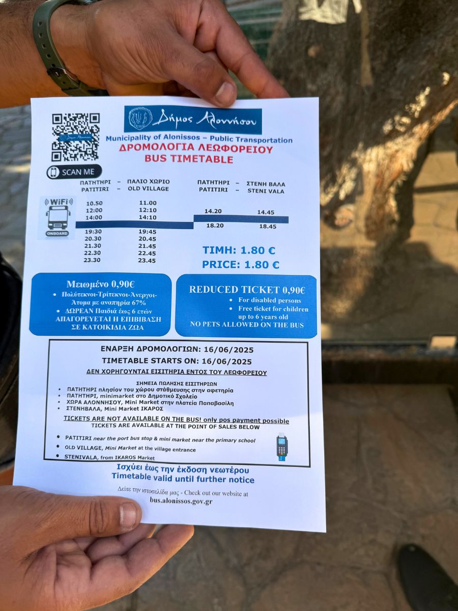 Hand holding the official Municipality of Alonissos bus timetable for 2025, detailing routes between Patitiri, Old Village, and Steni Vala, including pricing, ticket rules, and payment instructions.