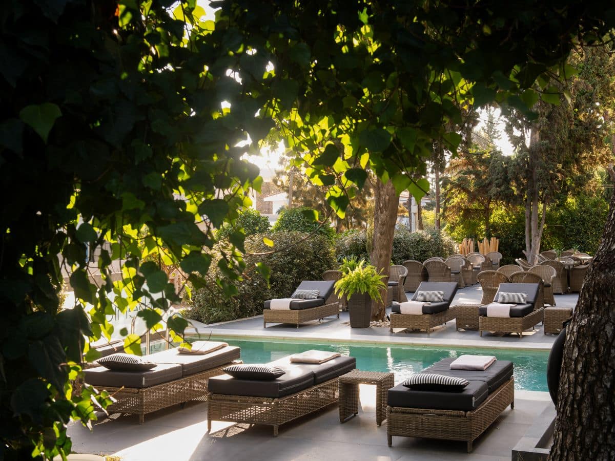 Outdoor pool area with lounge chairs and greenery.