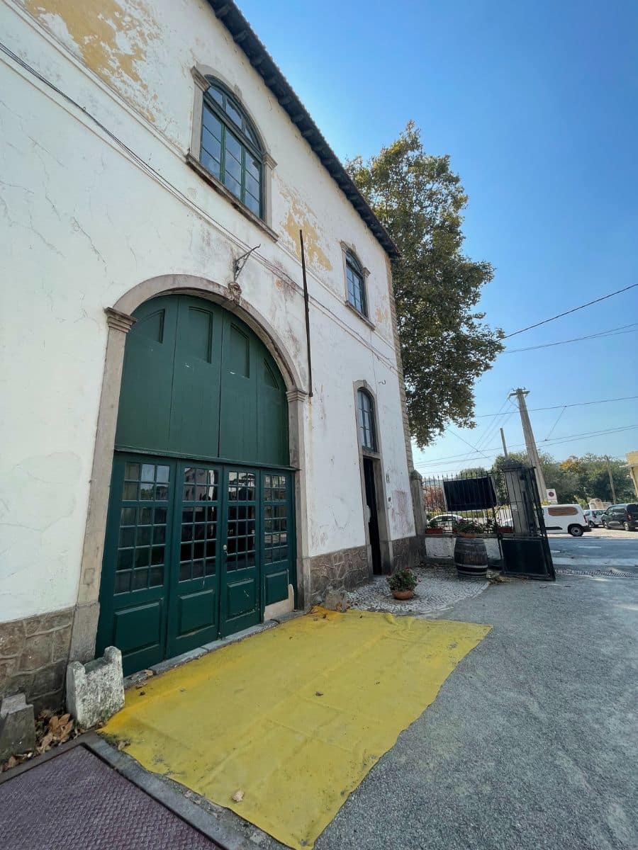 Whitewashed historic building with green arched doors and windows, set against a clear blue sky.