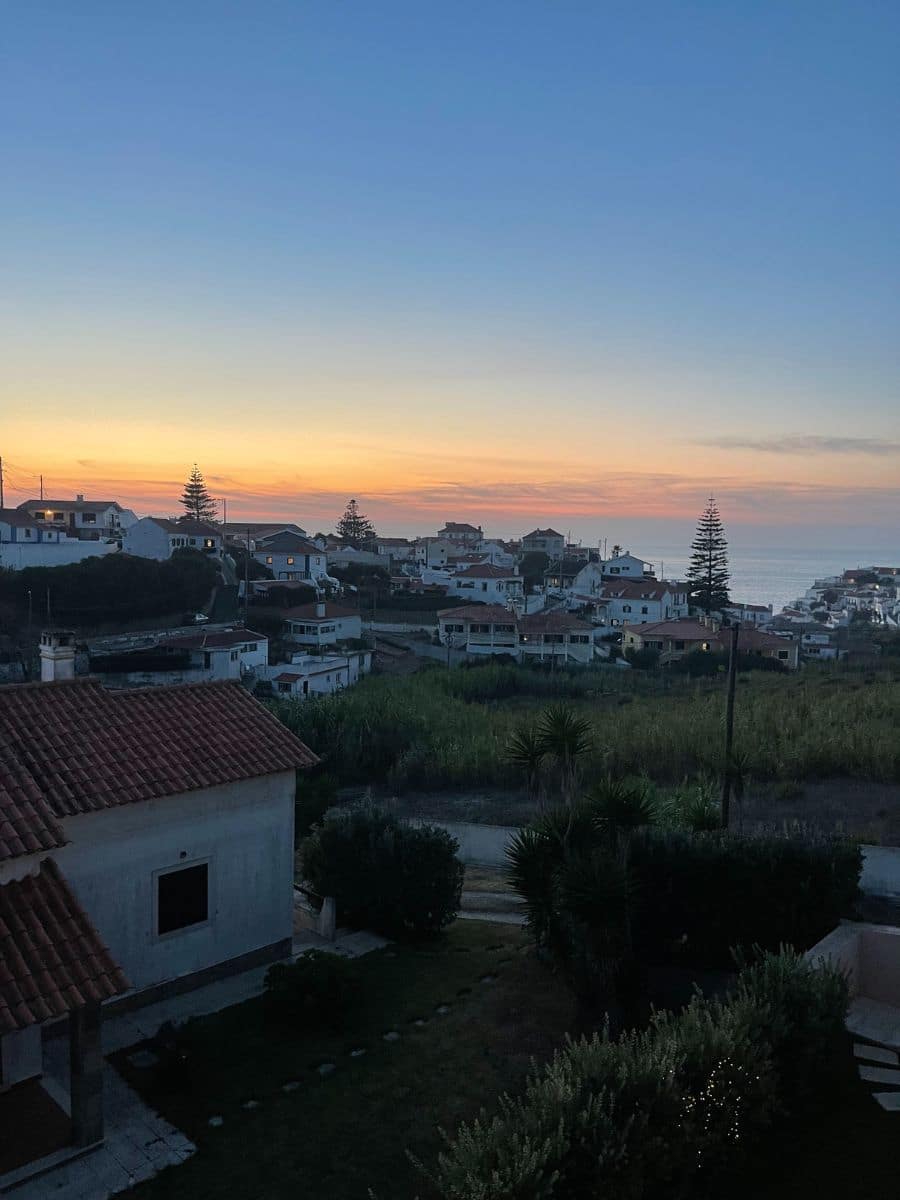 Soft twilight colors gently illuminating the village of Azenhas do Mar, with the ocean in the distance.
