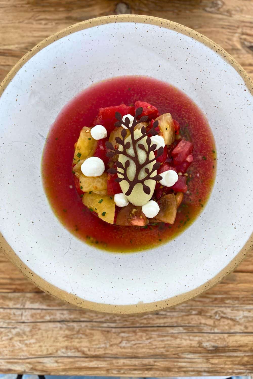 Top view of a plated dessert featuring sponge cake with berry compote and decorative cream on a rustic wooden table.