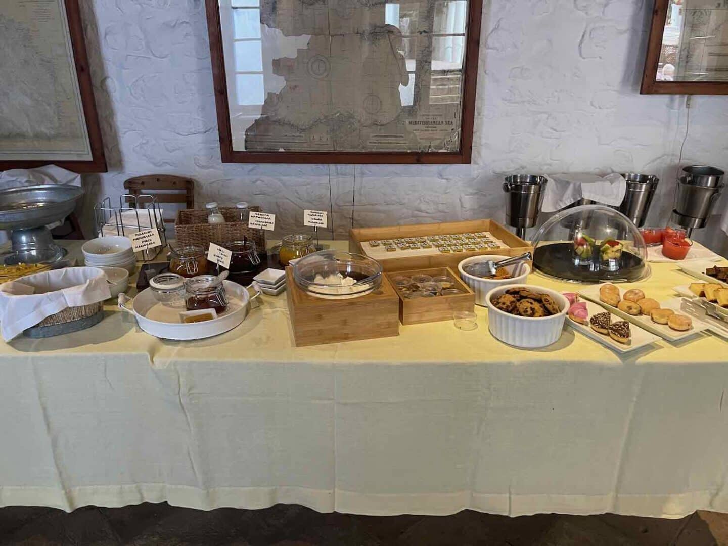 Hotel bar in Hydra offering a casual dining experience, with a neatly organized buffet and a selection of spirits on shelves, reflecting a blend of traditional and modern Greek hospitality.