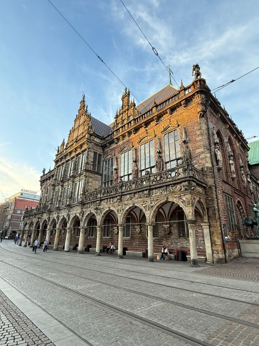 Bremen Town Hall with its ornate Gothic architecture, arched windows, and richly decorated façade under a blue sky.