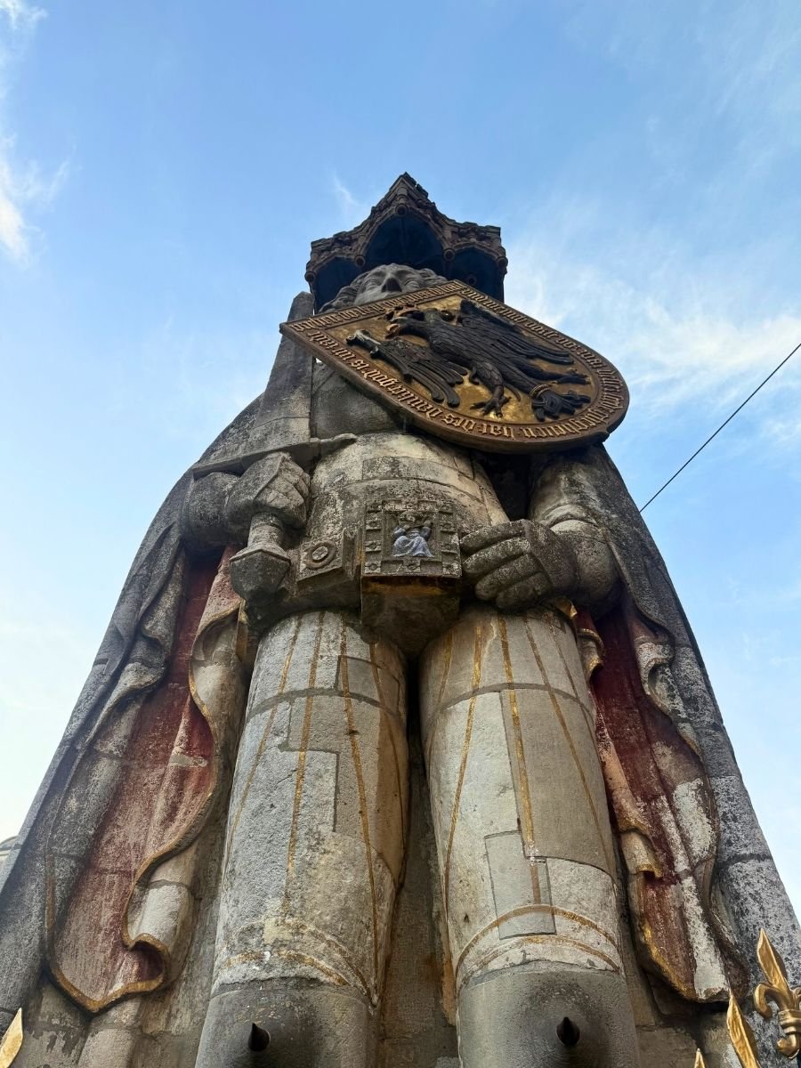 Low-angle view of the Roland Statue in Bremen, showing its detailed stonework and golden shield with a black eagle.