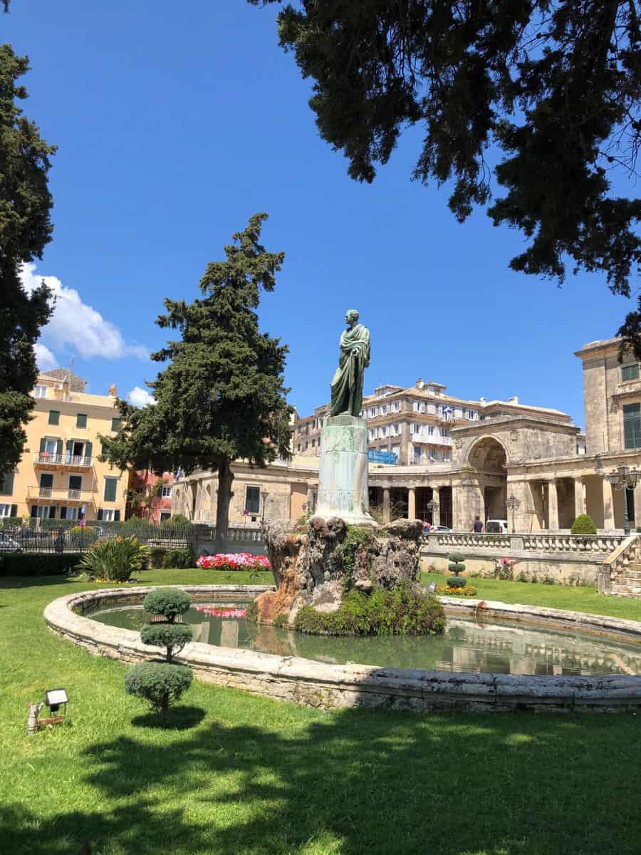 Statue in Corfu with historical buildings in the background.