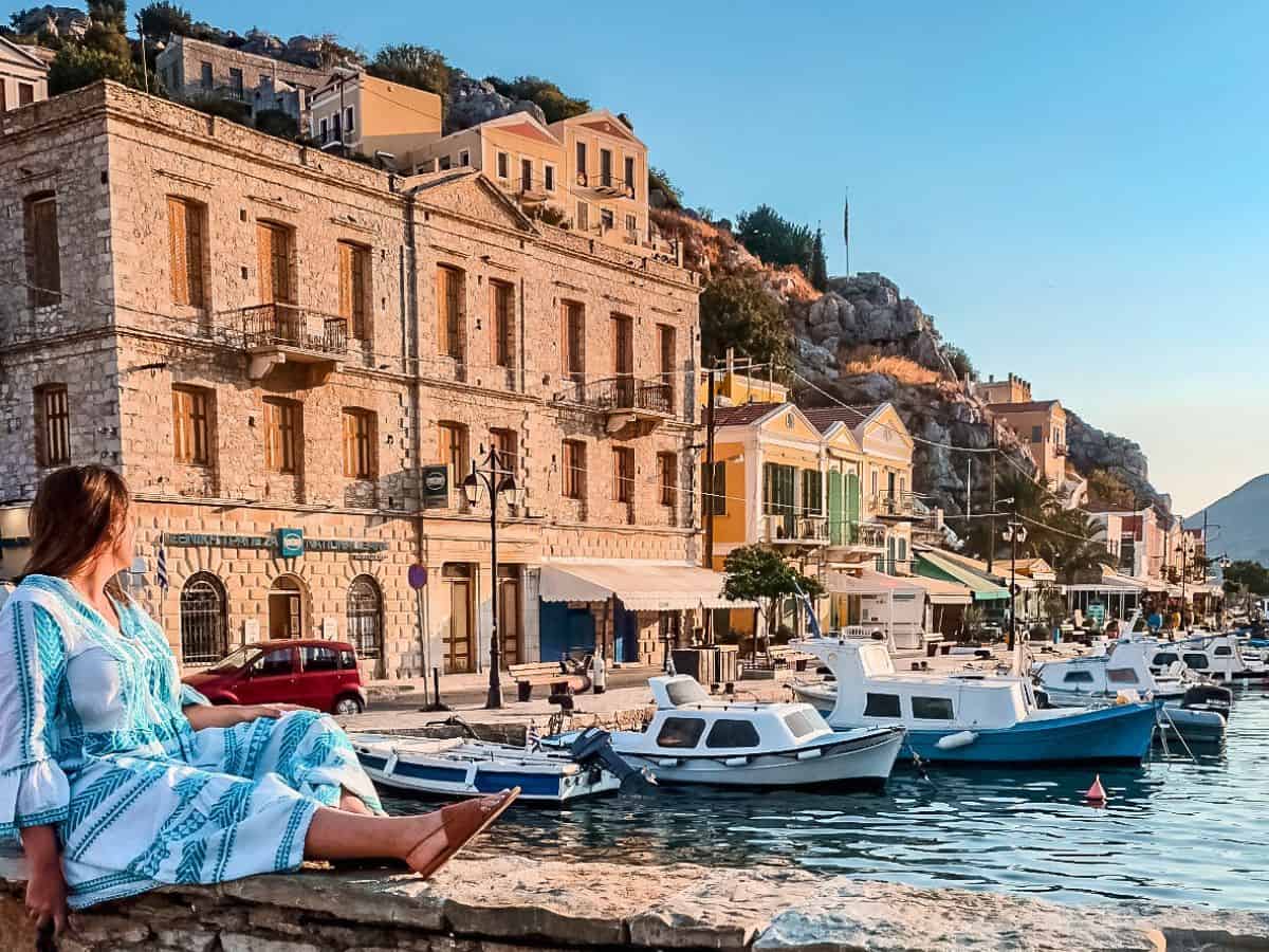 A woman sitting on the ledge looking out at the sea