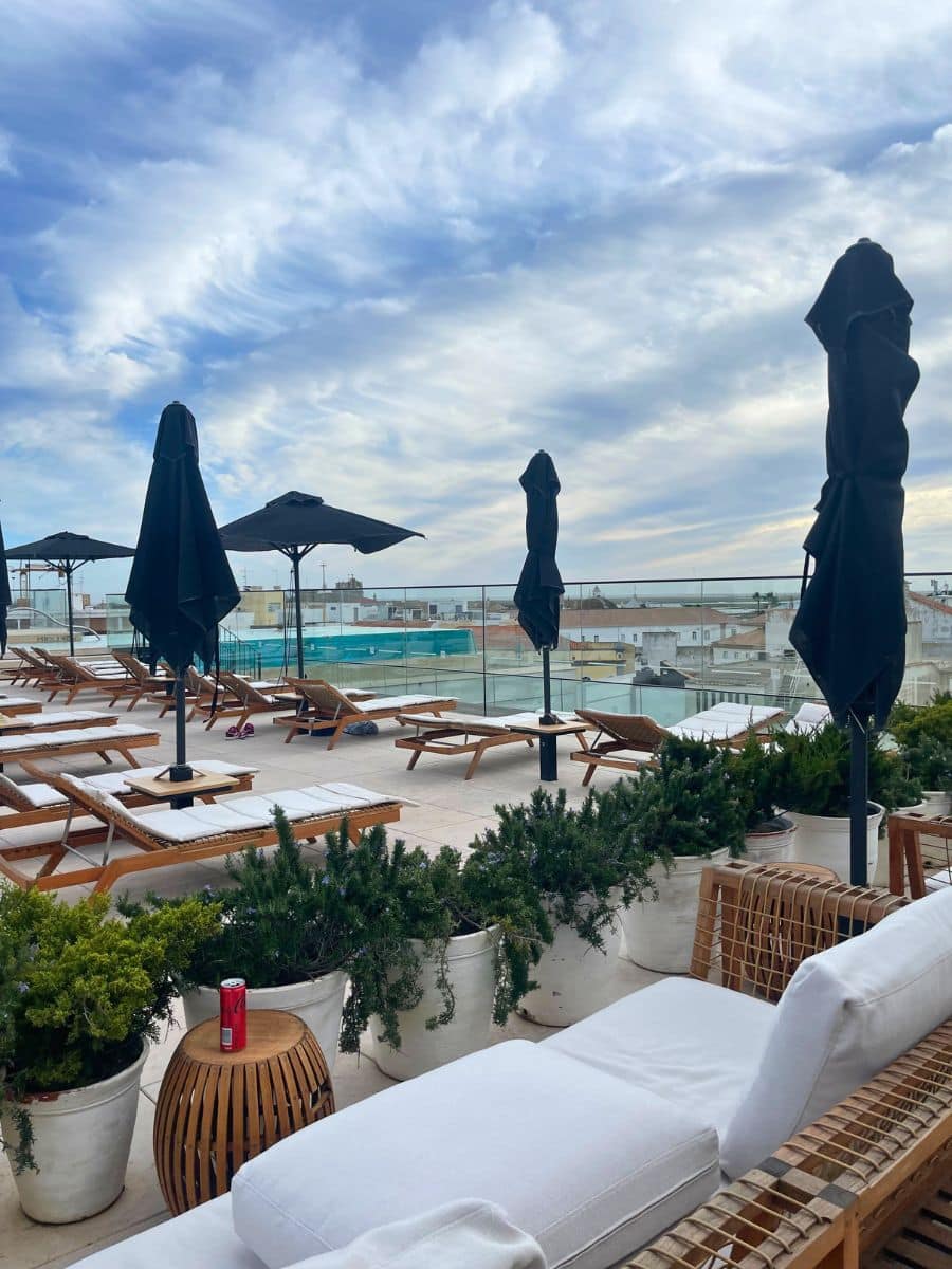 Sun loungers and umbrellas arranged on the rooftop deck with city views.