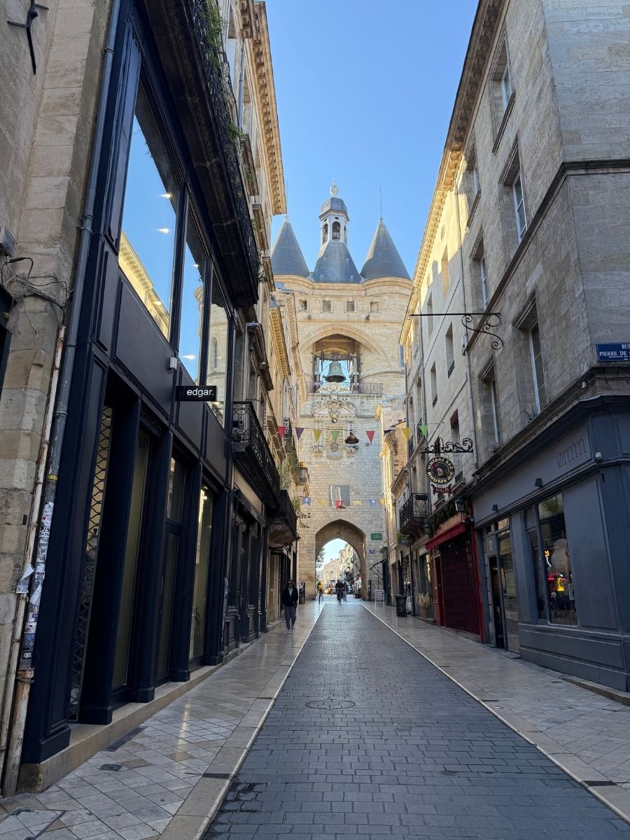 The Grosse Cloche bell tower of Bordeaux, France, framed by historic buildings and cobbled street in Rue Saint-James