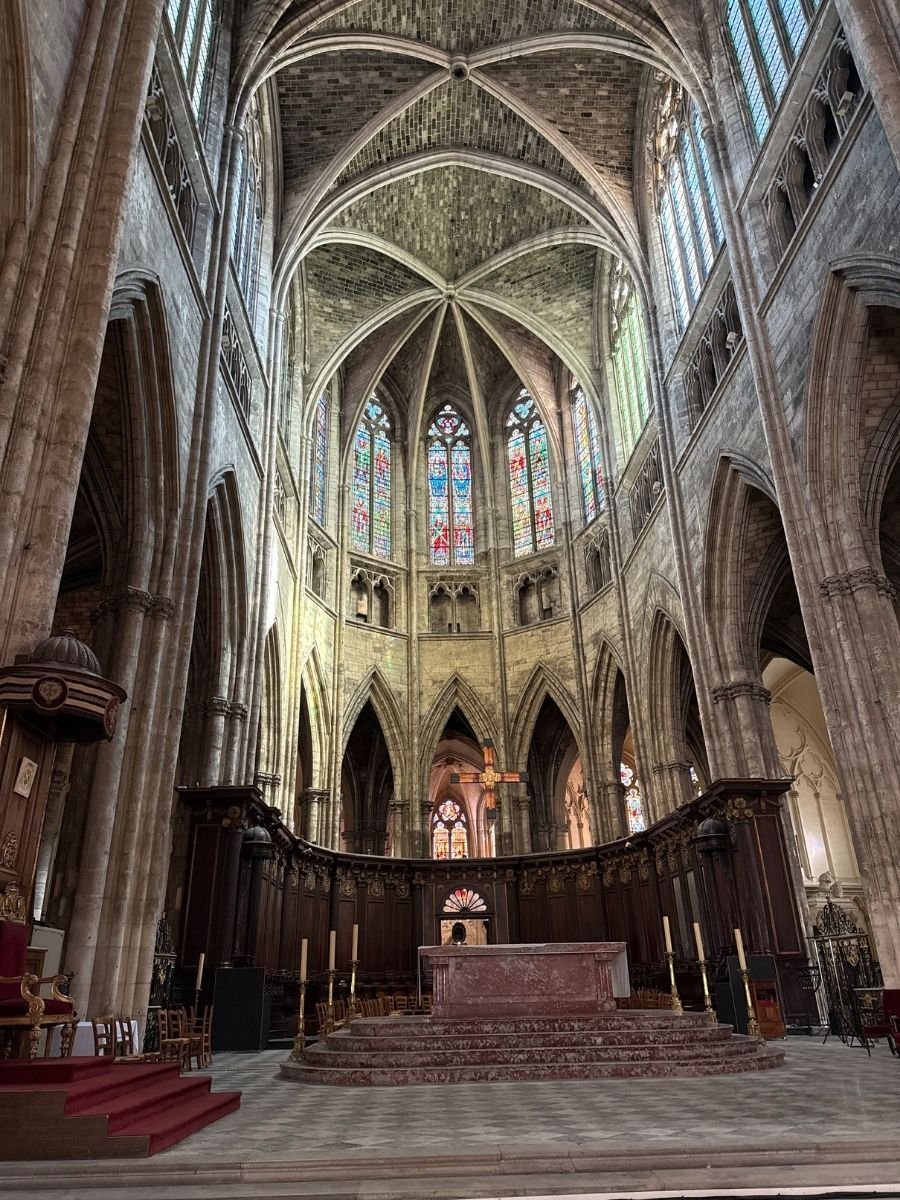 Interior of Bordeaux Cathedral (Cathédrale Saint-André), adjacent to Tour Pey-Berland, showcasing its stained-glass windows, vaulted ceilings, and Gothic arches.