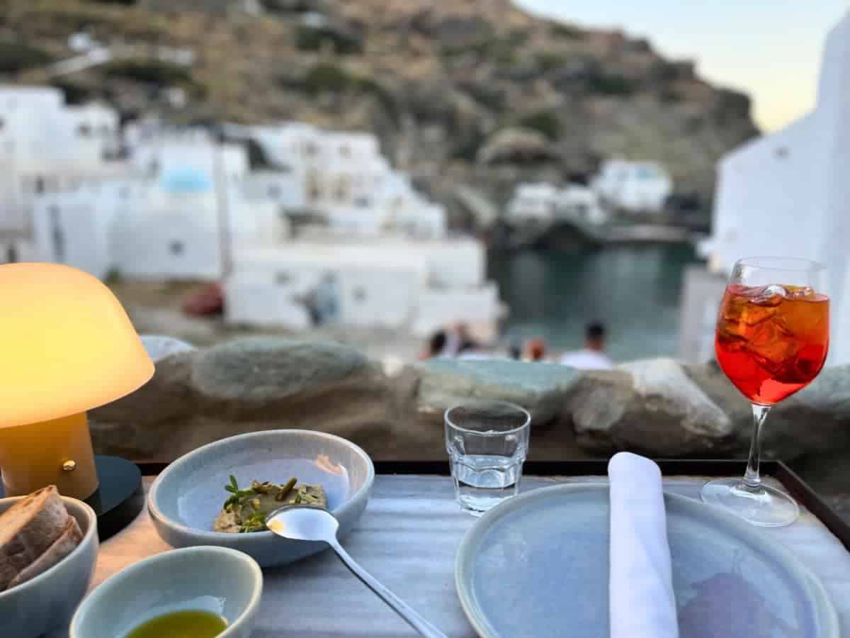 An outdoor dining table with aperol spritz and plated dishes. 