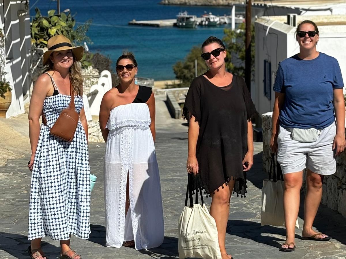 Four women standing in the road with the sea in the background.