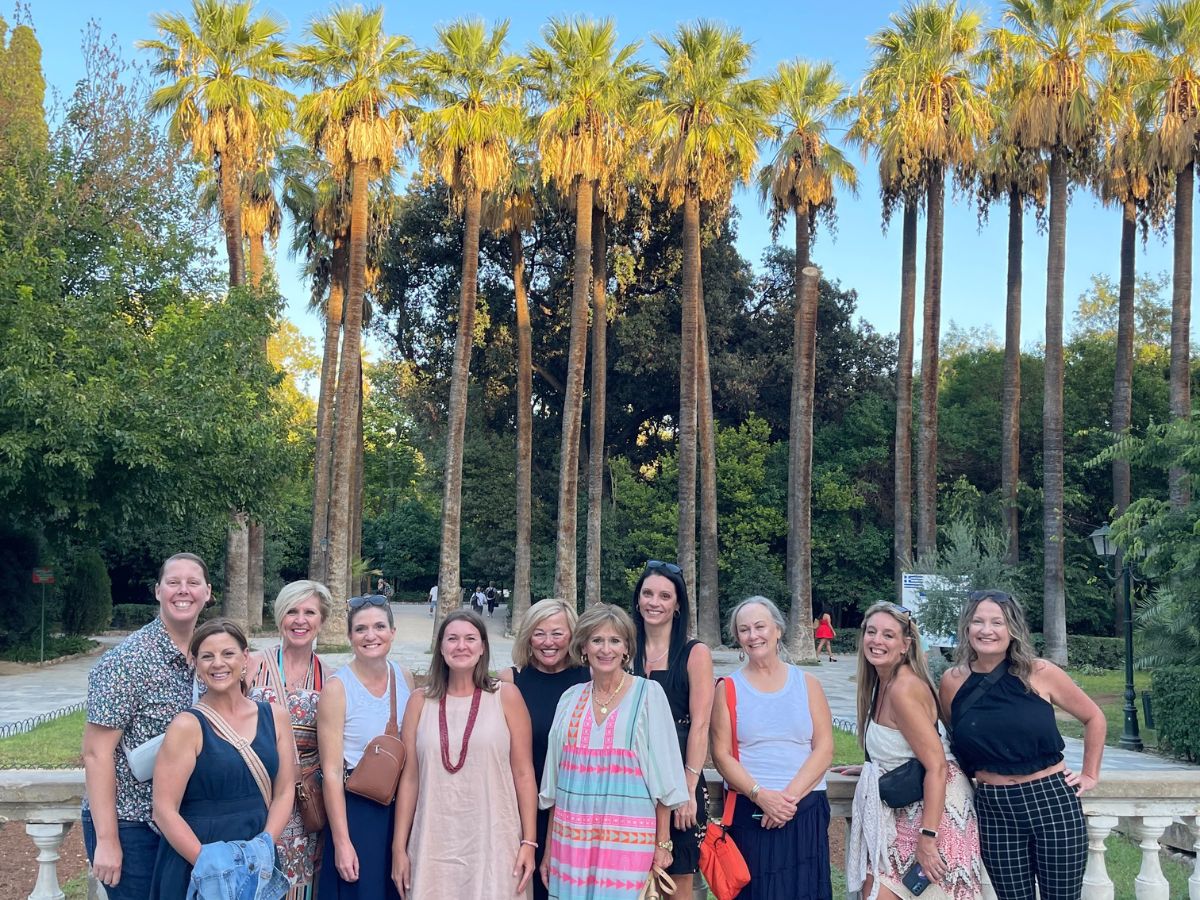 A group of women in front of a bunch of palm trees.