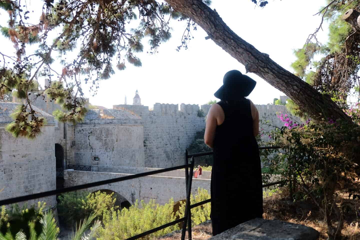 How to heal a broken heart A woman standing alone looking at a castle in greece. How to heal a broken heart with travel