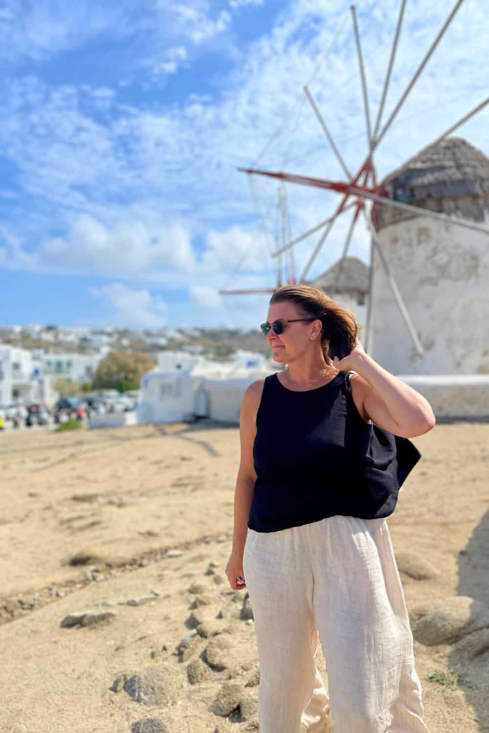 woman standing alone in front of the windmills in mykonos