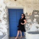A woman in Greece standing against a blue door