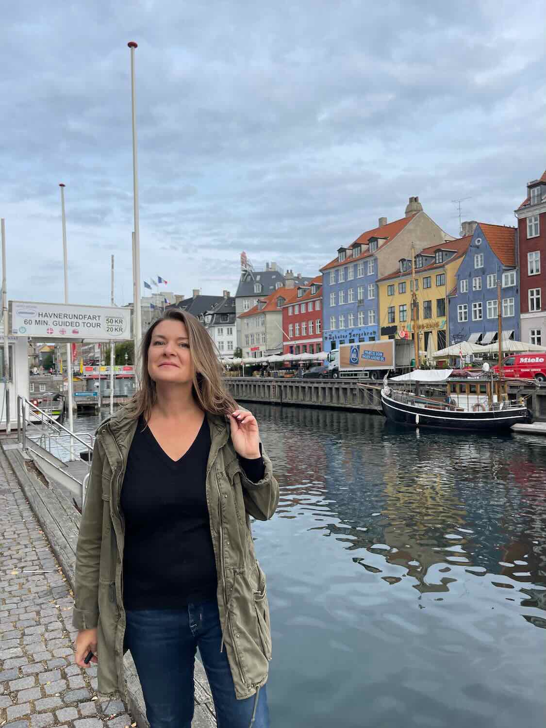 A woman alone in Copenhagen standing in from of the canal. 