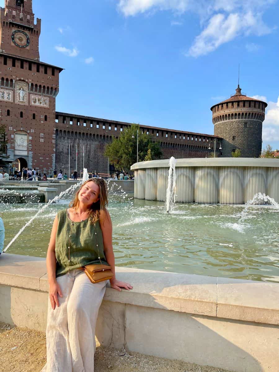 a woman sitting solo at the fountain in Milan. Milan solo travel activity of exploring the castle. 