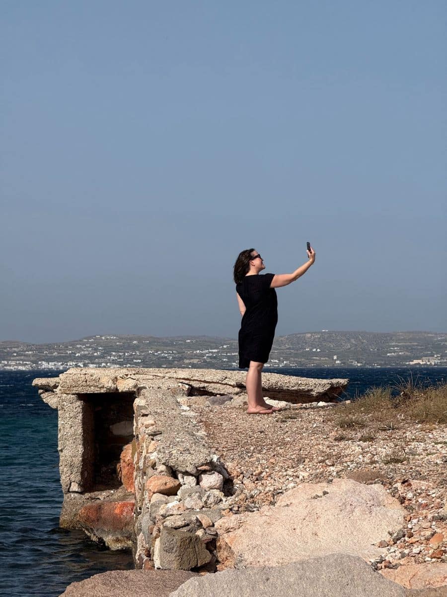 Solo female traveler capturing the moment on a Greek island coastline