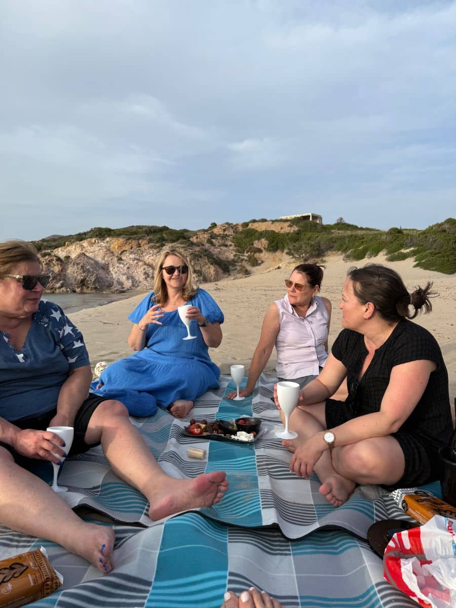 Women enjoying a picnic with wine on the beach in Milos during a female-only group tour