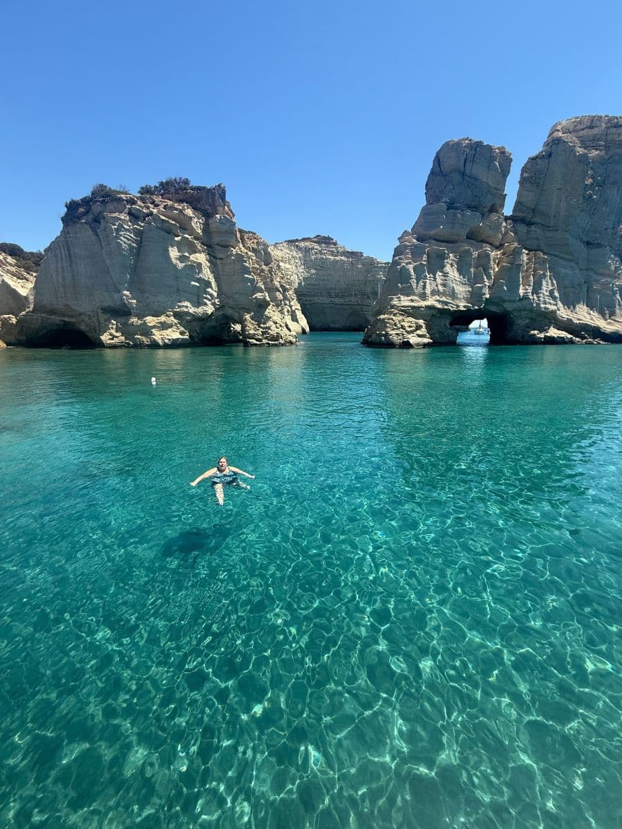 Woman swimming in crystal clear waters at Kleftiko, Milos on a Greek islands women-only tour