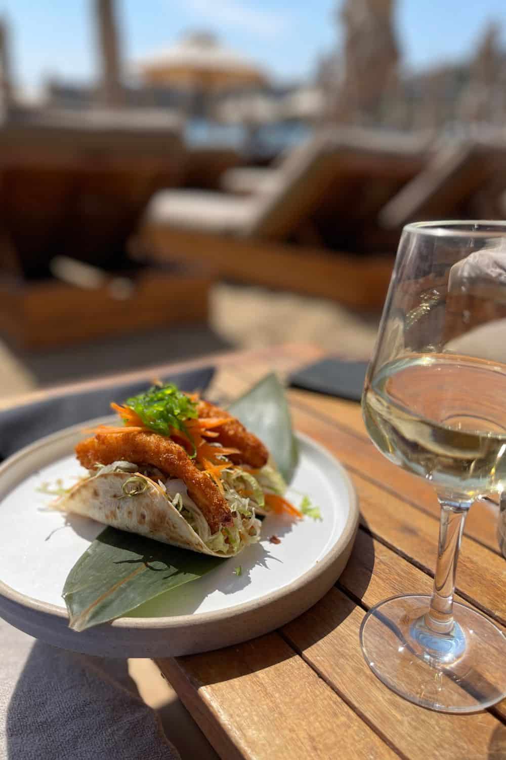 Fish tacos in Mykonos on a plate with a glass of wine