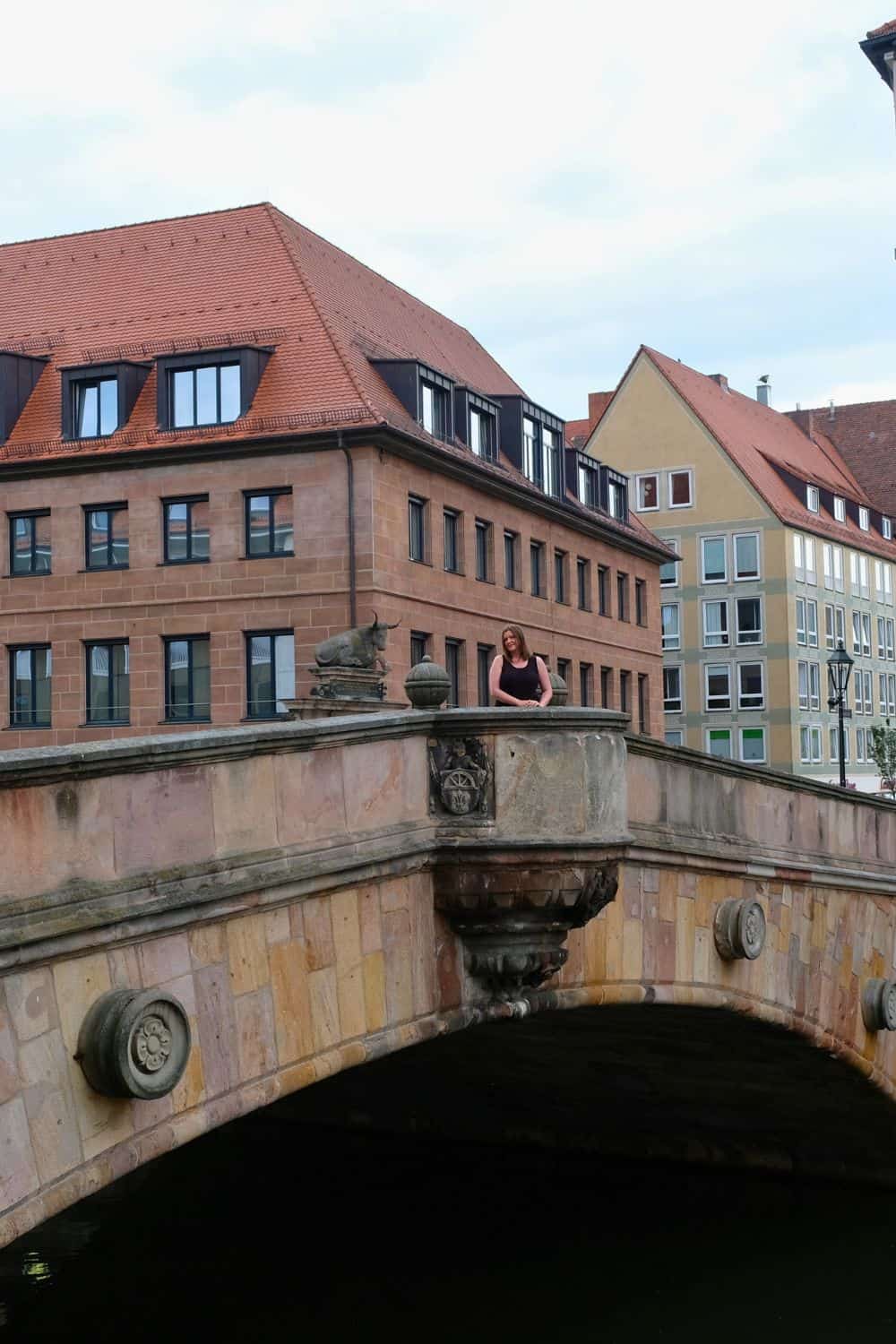 A woman leaning on an ornate bridge over the Pegnitz River in Nuremberg, Germany, contemplating the next destination on her day trip itinerary from the city.
