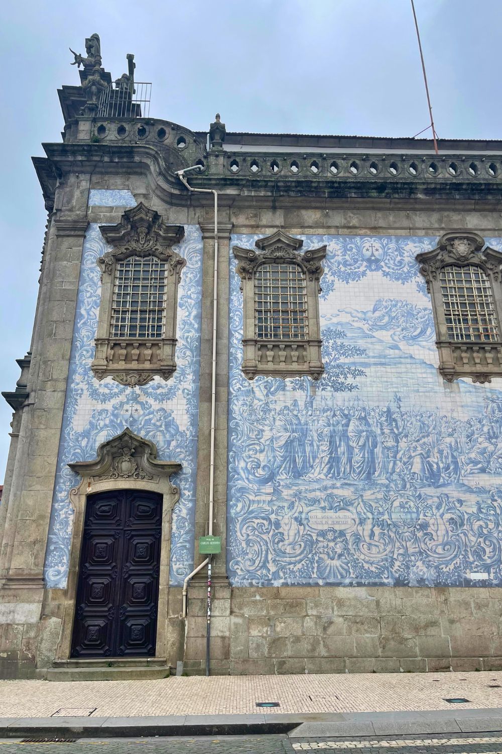 Historic building in Porto with blue azulejo tiles, ornate windows, and a grand wooden door.