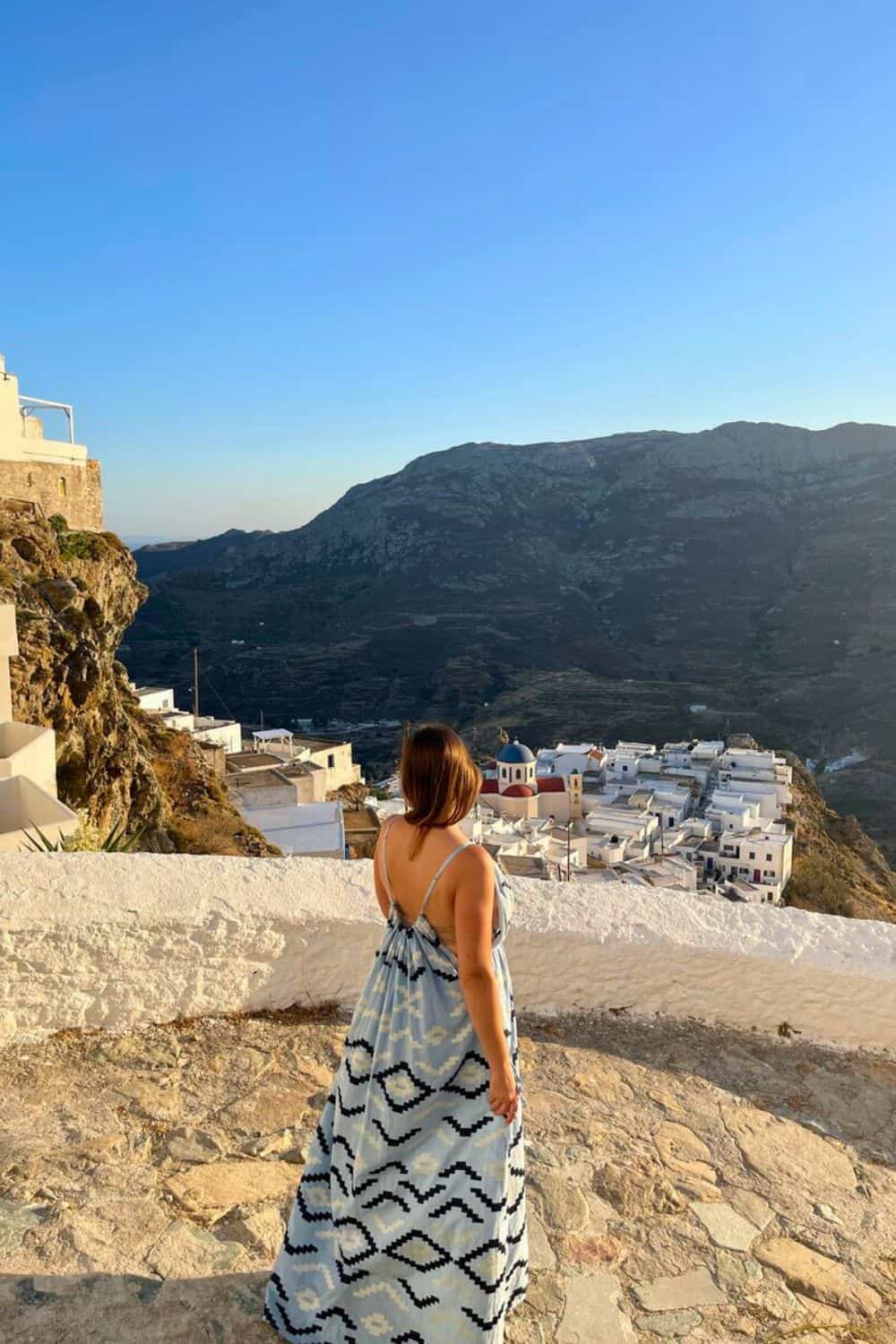 A woman walking alone looking at the small village in the distance. 