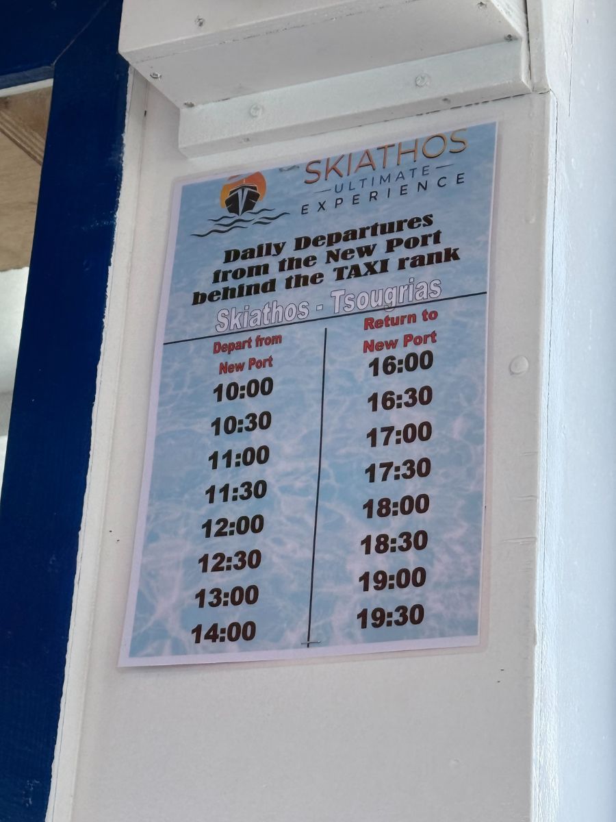 A posted schedule for the Skiathos–Tsougria boat route, showing daily departure and return times from the new port behind the taxi rank.