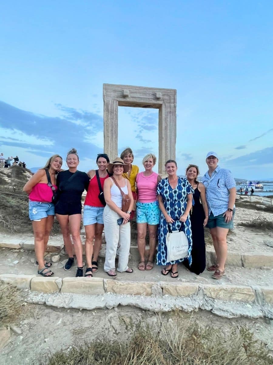 A small group of travelers posing together in front of an ancient stone archway at sunset, enjoying a cultural tour experience.