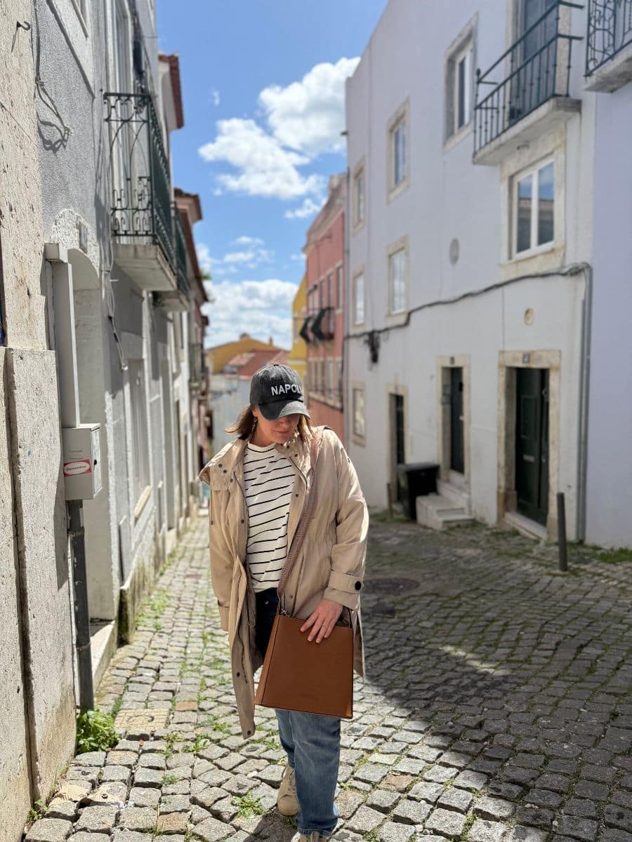 Casual urban outfit featuring a striped shirt and functional antitheft purse during a solo adventure.