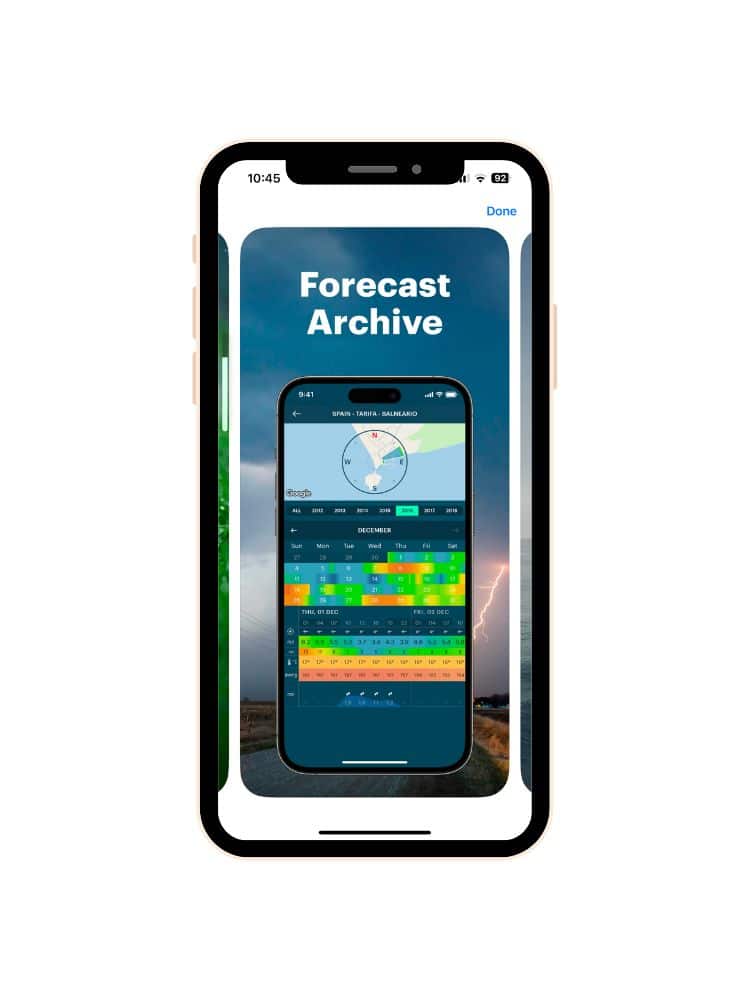 Phone screen showing the Windy app's 'Forecast Archive' feature with weather data over a background image of a landscape under a cloudy sky.