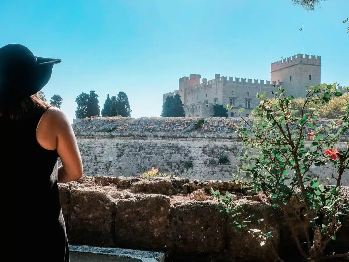 a woman looking out a the old town of Rhodes in the background