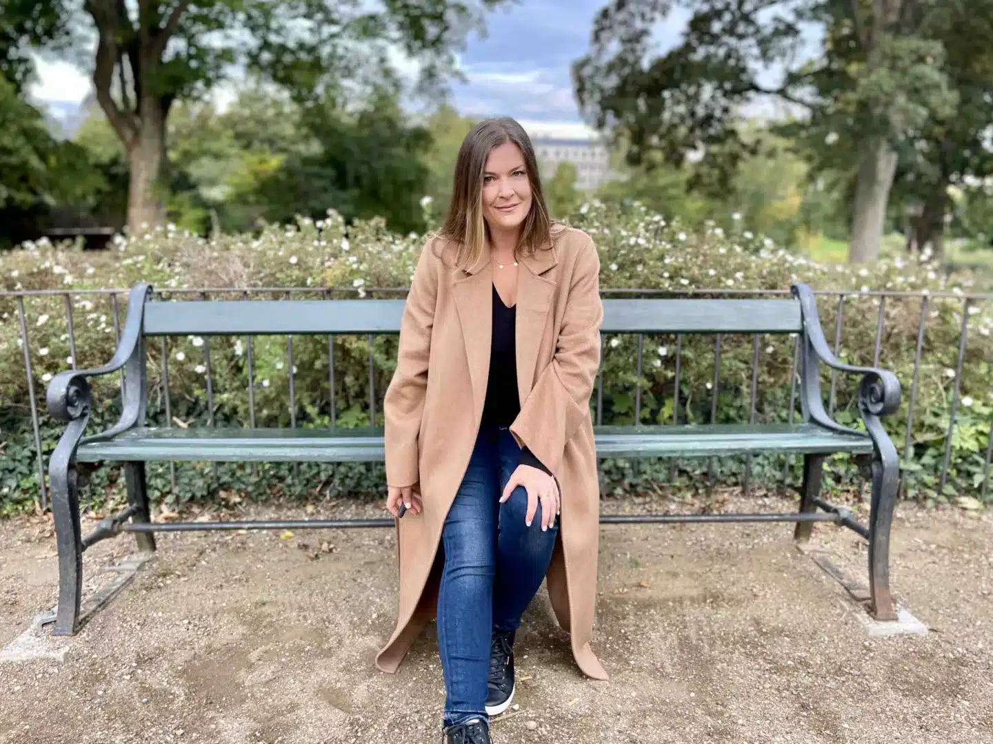 A woman solo traveling alone and sitting a park bench. 